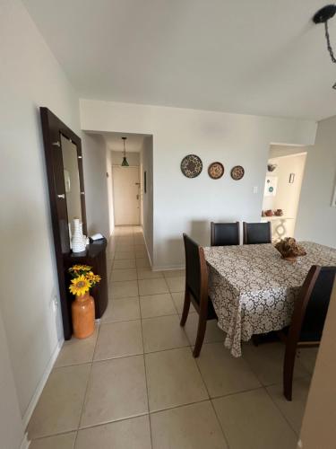 a dining room with a table and chairs and a hallway at Pé na areia incrível in Piçarras