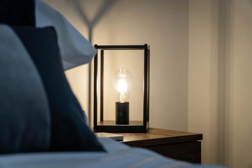a lamp on a table next to a bed at Flat in Royston Town Centre in Royston