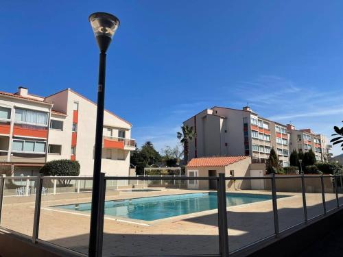 un lampadaire à côté d'une piscine avec des bâtiments dans l'établissement Appartement 2 pièces 4 couchages ARGELES SUR MER AR580-035, à Argelès-sur-Mer