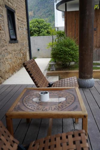 a coffee table and two chairs on a deck at the Wild Luxury Holiday Inn in Xingping