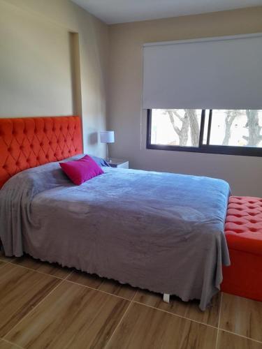 a bedroom with a bed with a red headboard and a window at Complejo Médanos in San Bernardo