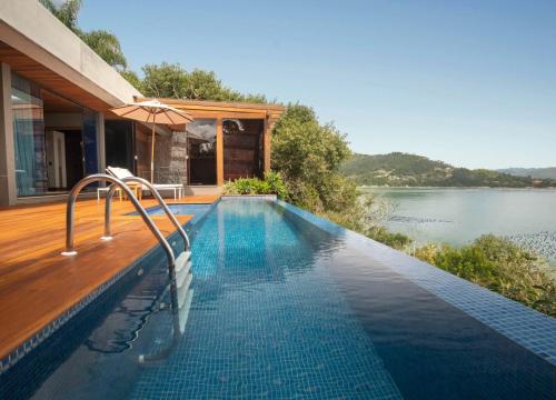 a house with a swimming pool next to a lake at Awasi Santa Catarina in Governador Celso Ramos