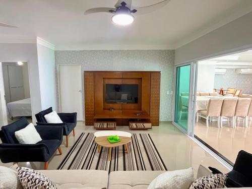 a living room with a couch and a tv at Casa Espaçosa com 5 Quartos Piscina Privativa 300m da Praia Ar condicionado em todos cômodos in São Sebastião