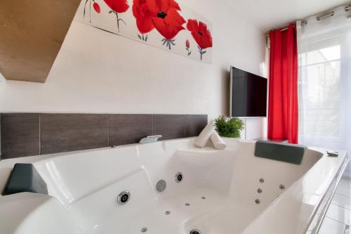 a bathroom with a large white tub with red flowers on the wall at 123home-Loft & spa in Montévrain