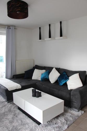 un salon avec un canapé noir et une table basse blanche dans l'établissement Appartement, à Saint-Louis