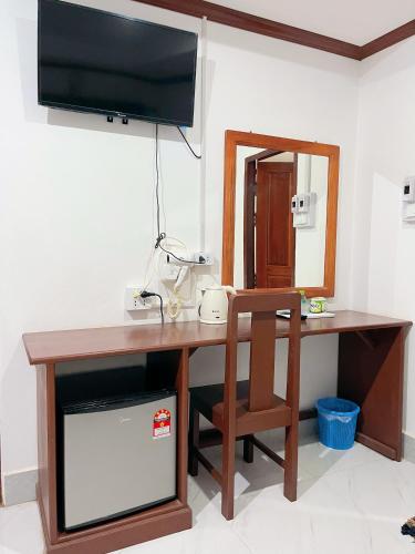 a desk with a chair and a television on a wall at Vangvieng Sisavang Hotel in Vang Vieng