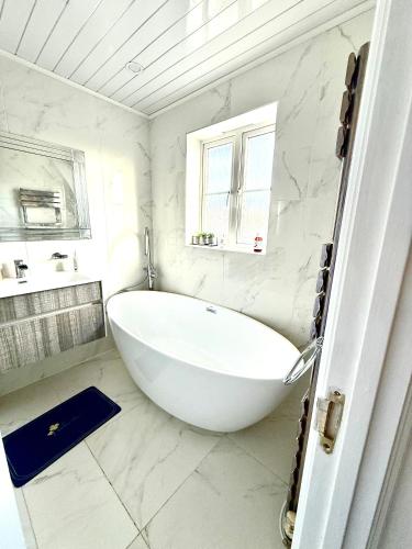 a white bathroom with a large tub and a window at Rose home in Haverhill