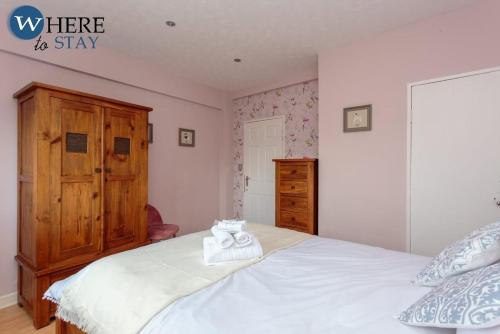 a bedroom with a white bed with a wooden dresser at Stylish 3 Bedroom Apartment, Edinburgh in Edinburgh