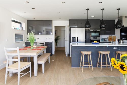 a kitchen and dining room with a table and chairs at Luxury designer coastal home for 10 with hot tub in West Wittering