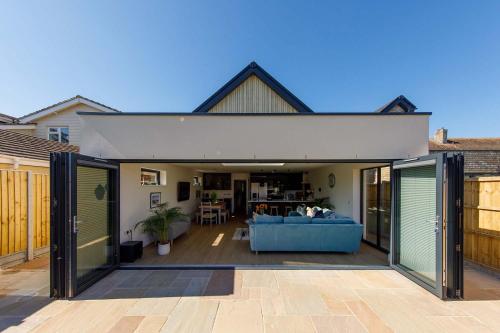 an open living room with a blue couch on a patio at Luxury designer coastal home for 10 with hot tub in West Wittering