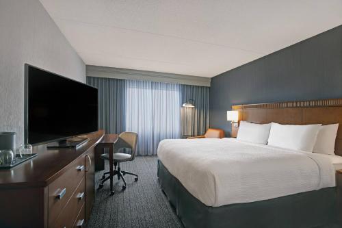 a hotel room with a bed and a desk with a television at Courtyard Chicago Elmhurst/Oakbrook Area in Elmhurst