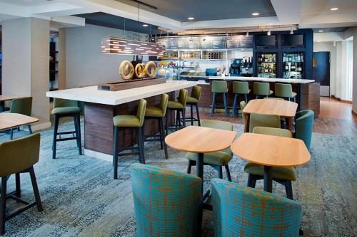a bar in a restaurant with tables and chairs at Courtyard by Marriott West Palm Beach Airport in West Palm Beach