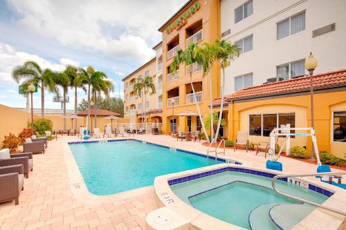 a pool in front of a hotel with palm trees at Courtyard by Marriott West Palm Beach Airport in West Palm Beach
