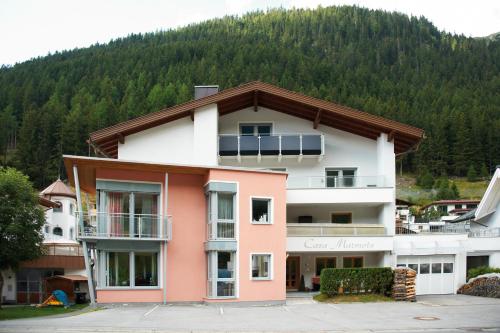 a pink and white building with a mountain in the background at Casa Marmota in Ischgl