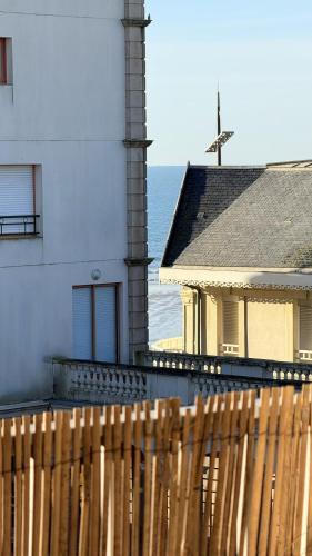 une maison avec une clôture en bois à côté de l'océan dans l'établissement Duplex aperçu mer chaleureux 3 personnes, à Les Sables-dʼOlonne