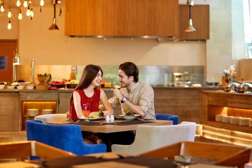 a man and woman sitting at a table in a restaurant at Courtyard by Marriott Bandung Dago in Bandung