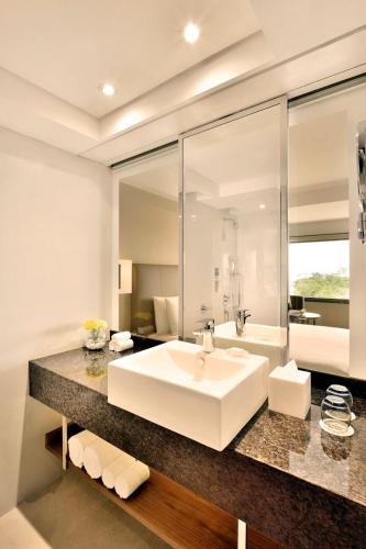 a bathroom with a large white sink and a tub at Courtyard by Marriott Chennai in Chennai