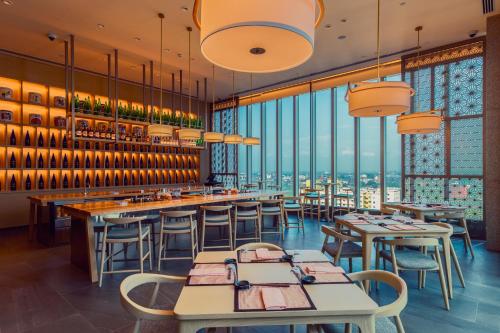 a restaurant with tables and chairs and windows at Cinnamon Life at City of Dreams in Colombo