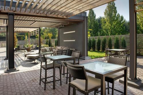 a patio with tables and chairs under a pergola at Courtyard Portland East in Portland