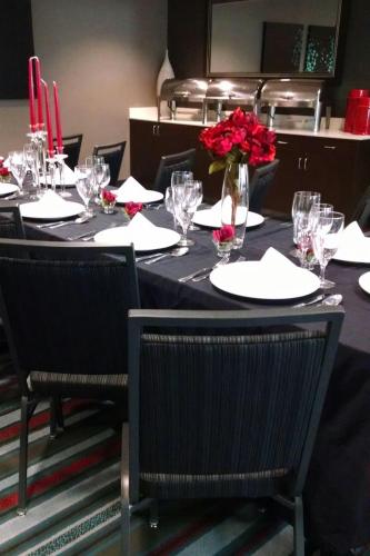 a table with glasses and a vase with red flowers on it at Courtyard by Marriott Wilmington Downtown/Historic District in Wilmington