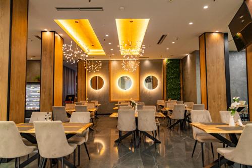 a restaurant with wooden tables and white chairs at Henry Resort & Spa in Golem