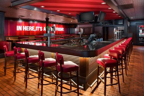 a bar with red chairs and a television in a restaurant at Courtyard Chicago Midway Airport in Bedford Park