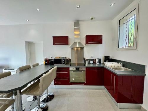 une cuisine avec des armoires rouges, une table et un évier dans l'établissement Le citron, Bel appartement en pleine nature à 2 minutes du centre ville, à Hyères