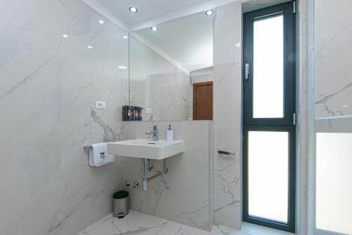 Un baño blanco con lavabo y espejo. en Apartmani Brela 15 luxury, en Brela