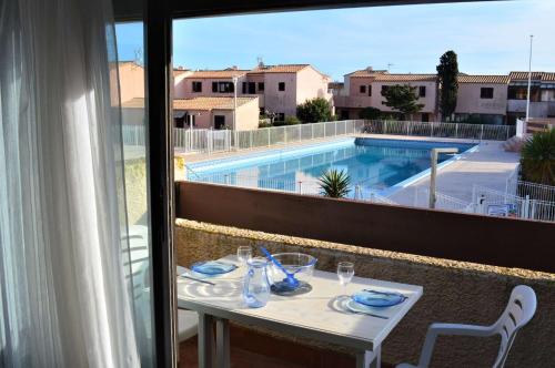 - une table sur un balcon avec vue sur la piscine dans l'établissement Appart Studio mezz 2 couchages PORT LEUCATE NATURISME PL010-453, à Leucate-Plage