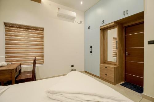 a bedroom with a bed and a desk and a window at Pearlspot Homestay in Munroe Island