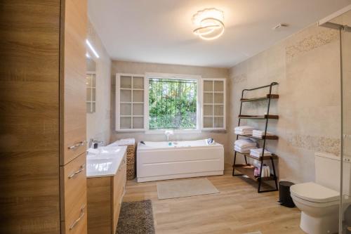 a bathroom with a tub and a sink and a toilet at La Villa Cyrano - Maison avec piscine privée! in Bergerac