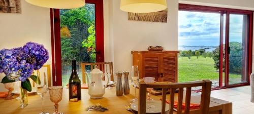 a dining room with a table with flowers and wine bottles at Villa Kermohic - en front de mer in Pleubian