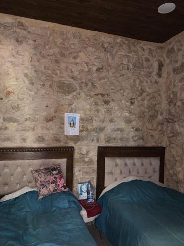 Un dormitorio con dos camas y una pared de piedra. en Back To Root, en Sahl ‘Almā