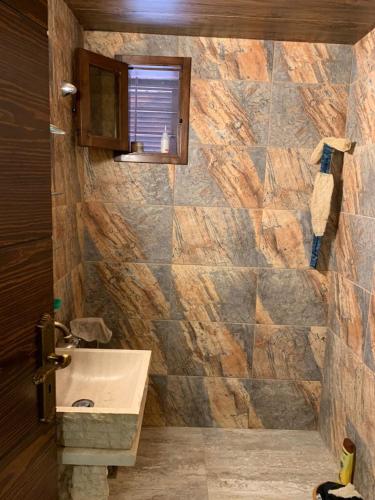 Un baño con lavabo y pared de piedra. en Back To Root, en Sahl ‘Almā