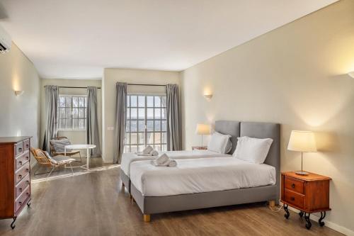 a bedroom with a bed and a dresser and two windows at Canaan Boutique Casa do Monte by Get Your Stay in Boliqueime