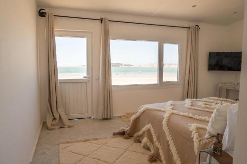 a bedroom with a view of the ocean through the windows at Dakhla Attitude in Dakhla