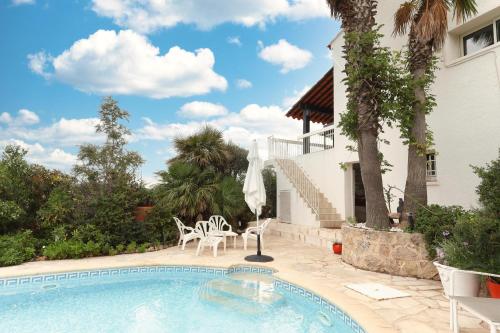 une piscine avec des chaises et une maison dans l'établissement La Maison de Laurence, aux Issambres