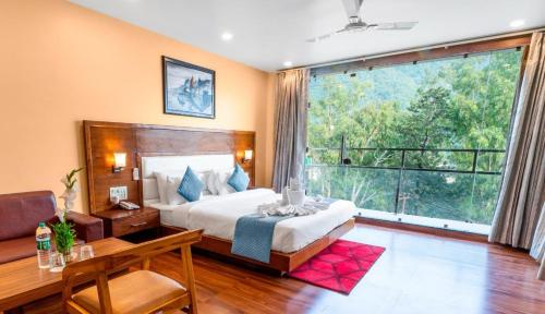 a bedroom with a bed and a large window at Hotel Divine Lakshmi Ganga in Rishīkesh