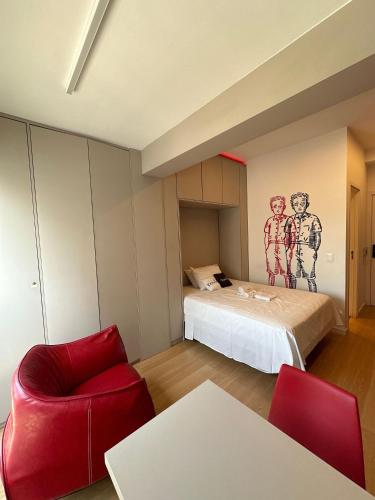 a bedroom with a bed and a red chair at TrevizZo Vergueiro in São Paulo