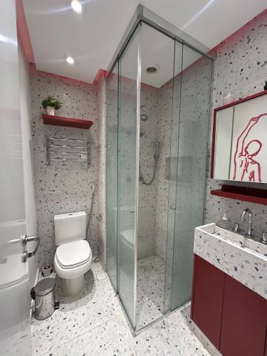 a bathroom with a toilet and a glass shower at TrevizZo Vergueiro in São Paulo