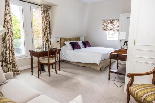 a bedroom with a bed and a desk and a table at Domaine de la Tortinière in Montbazon