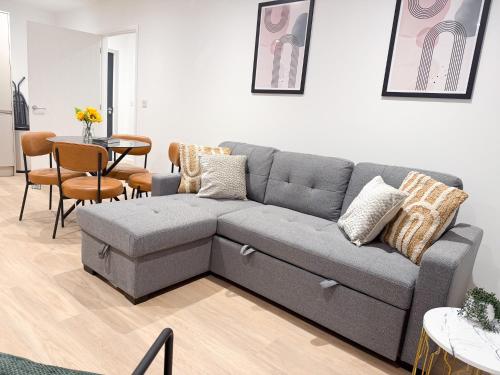 a living room with a gray couch and a table at Spacious Modern 1 Bed Apartments in St Neots - Perfect for Contractors & Professionals - Free Parking - WiFi - Fully Equipped Kitchen - Smart TV Ideal for Work Stays and Long Projects in Saint Neots