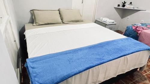 a bed with a blue and white blanket on it at Altas Horas Hostel in Areia