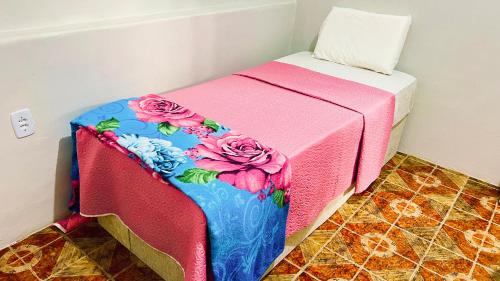 a small bed with a pink and blue blanket at Altas Horas Hostel in Areia