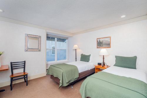 a bedroom with two beds and a chair and a window at Standard Double Room in Telluride