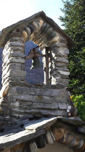 a window of a stone house with a bell in it at Casa San Cristoforo Atelier in Maggia