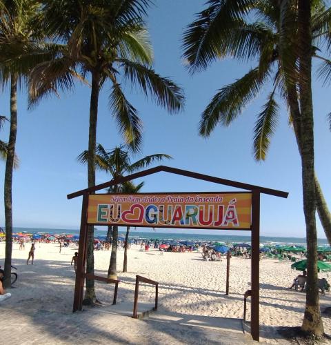 a sign on a beach with palm trees at Pousada Ideal Guarujá - Estúdios Mobiliados, Ar-Condicionado e Cozinha in Guarujá
