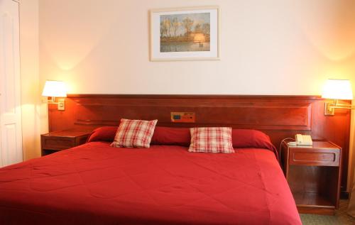 a bedroom with a red bed with two red pillows at Hotel Reviens in Pinamar