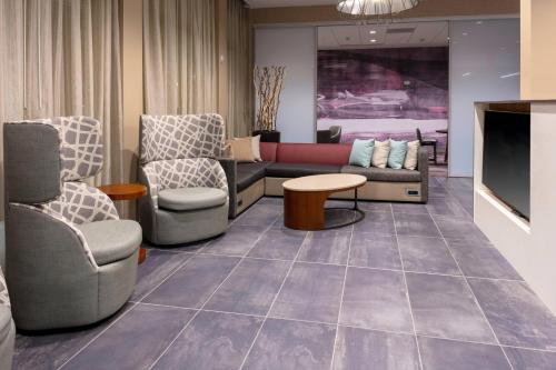 a waiting room with chairs and a couch and a tv at Courtyard by Marriott Indianapolis West-Speedway in Indianapolis