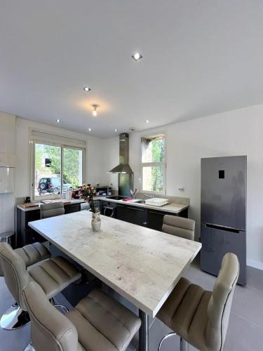 - une cuisine avec une grande table et des chaises en marbre dans l'établissement Le Kiwi, bel appartement moderne en pleine nature, à Hyères